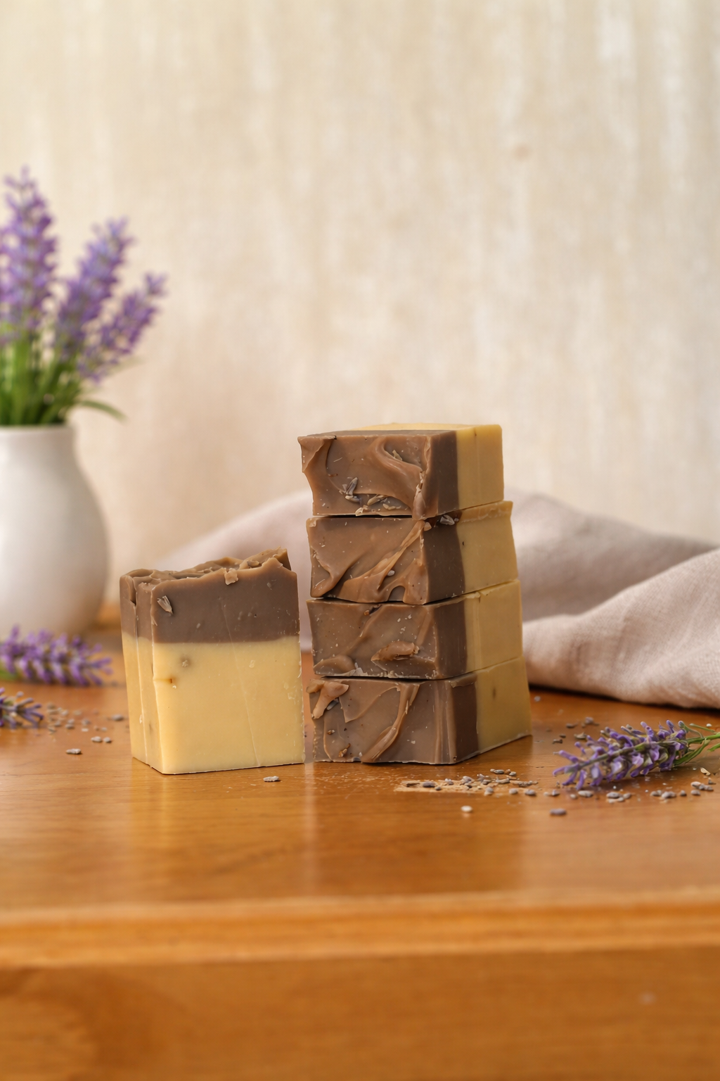 Stack of soap bars with a natural design on a wooden surface with lavender flowers.