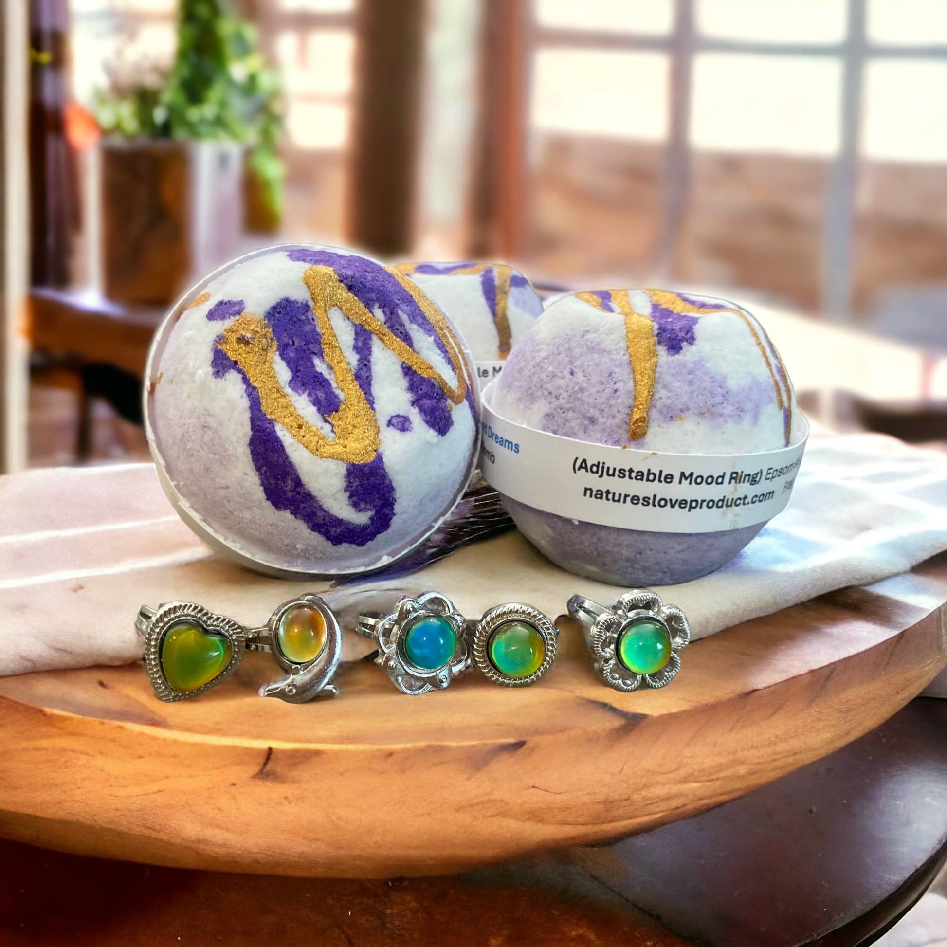 Bath bombs with decorative elements  of purple and gold, and mood rings on a wooden surface.