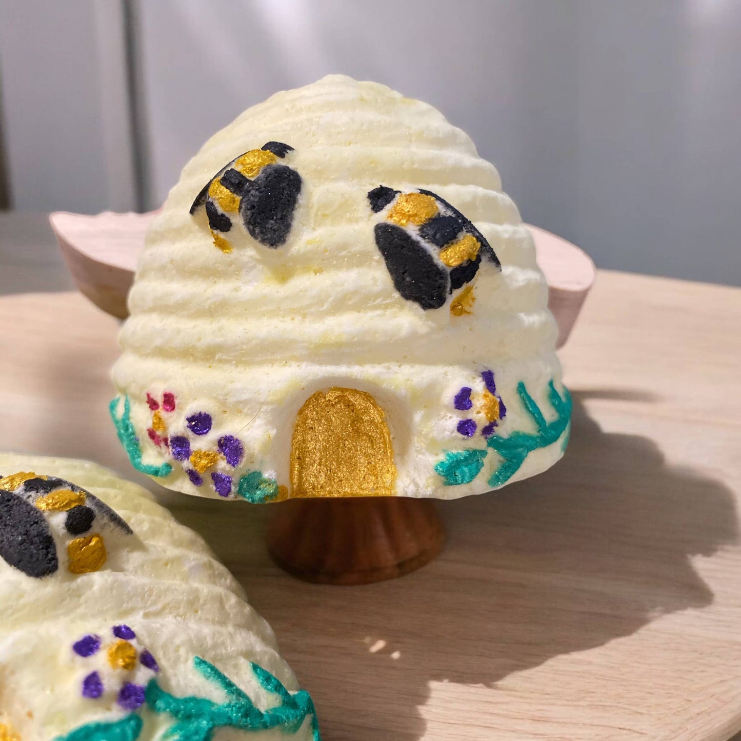 Decorative bath bomb shaped like a beehive with bee figures on a wooden surface.