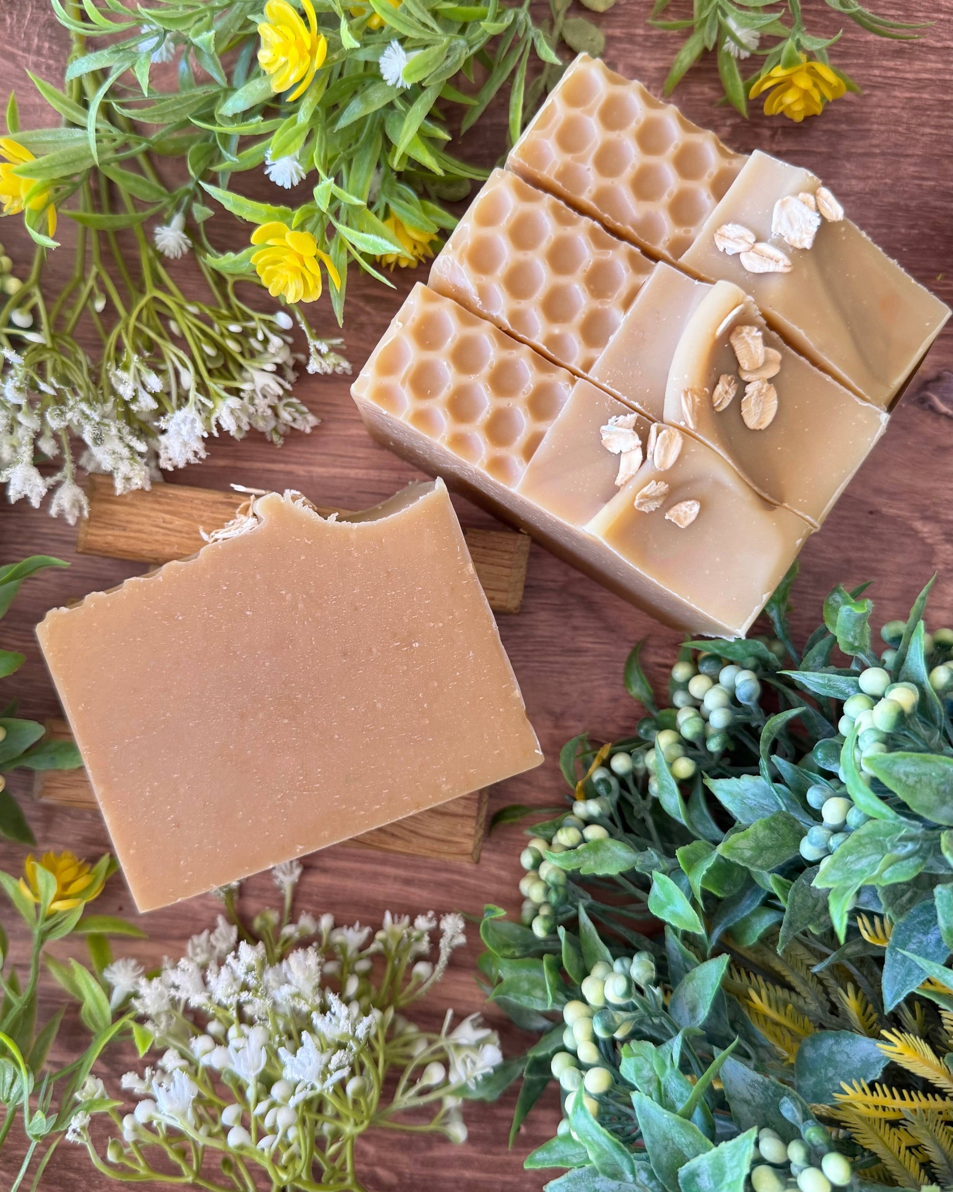 Beige soap bars with honeycomb design on a wooden surface with greenery