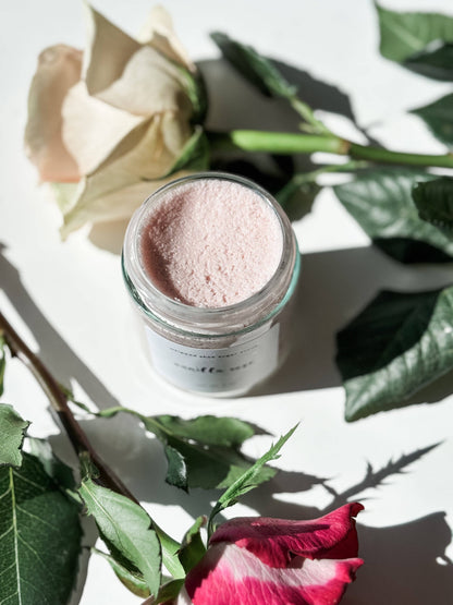 Jar of pink body sugar scrub with flowers on a white background
