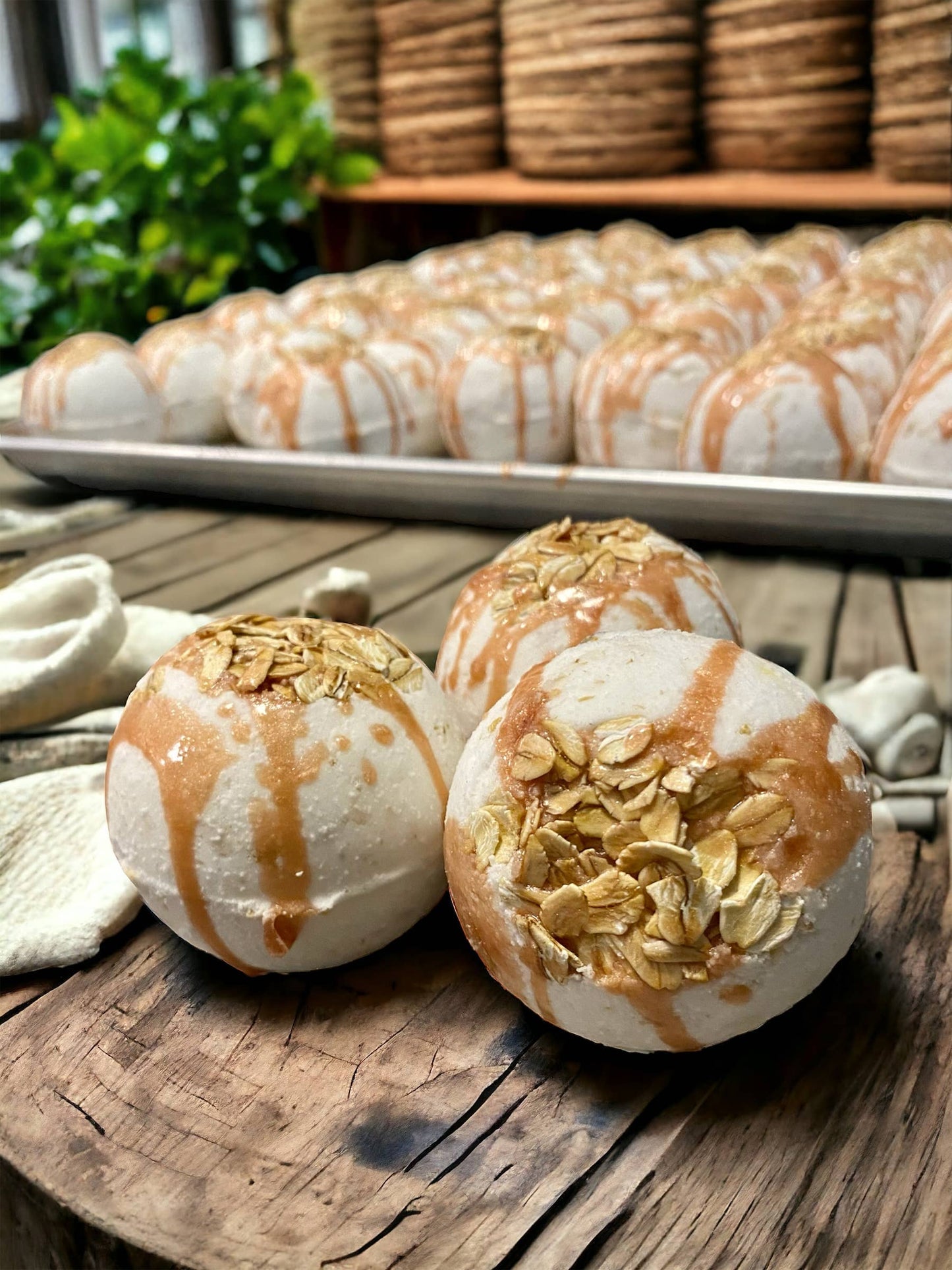 Bath bombs with oatmeal on a wooden surface, with more bath bombs in the background.
