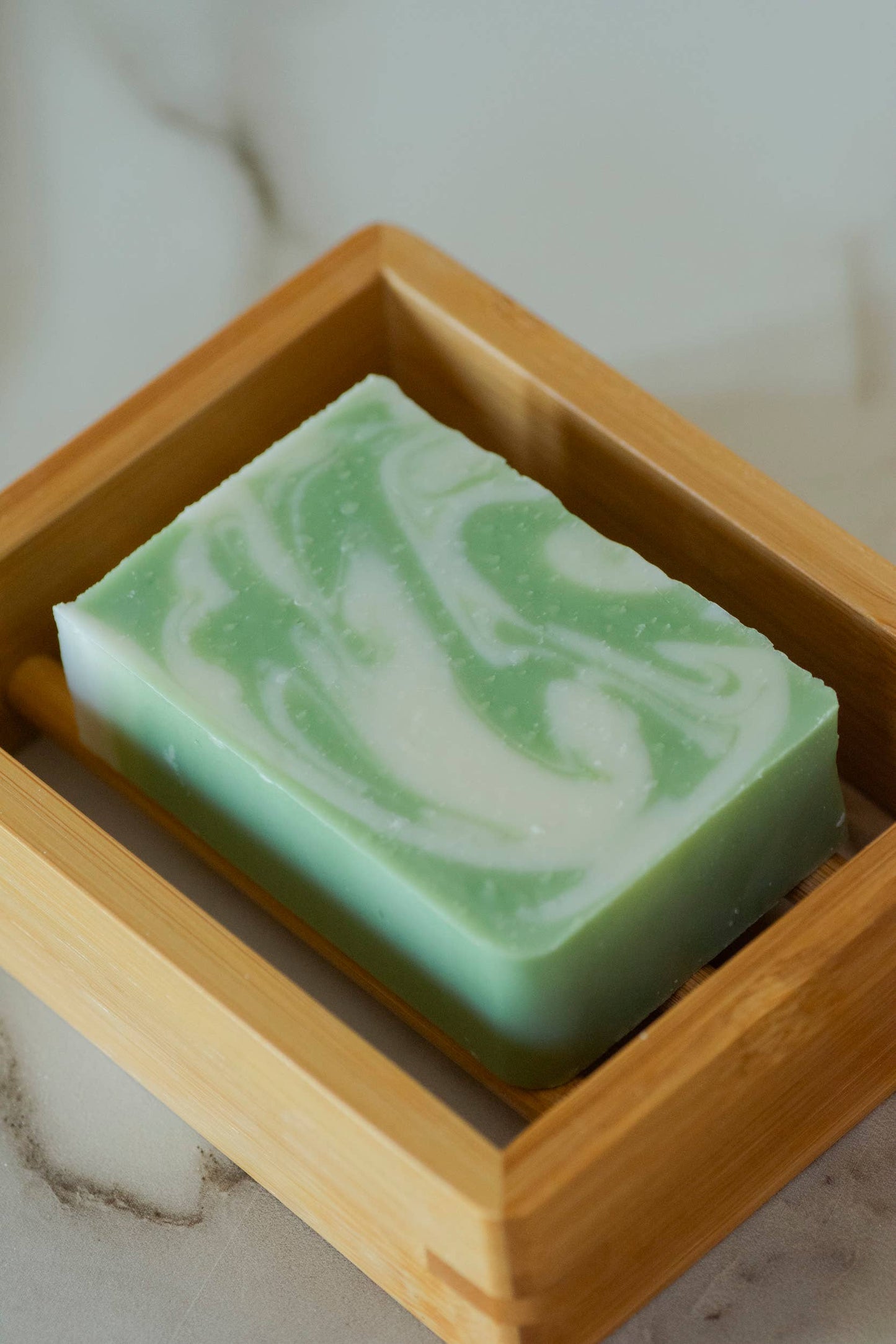 Wooden bamboo soap holder with a green and white soap bar.