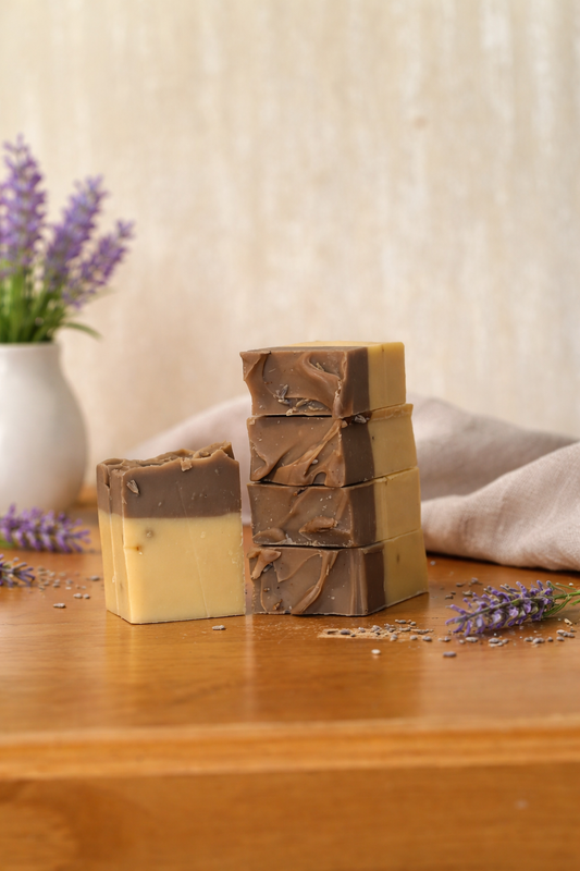 Stack of soap bars with a natural design on a wooden surface with lavender flowers.