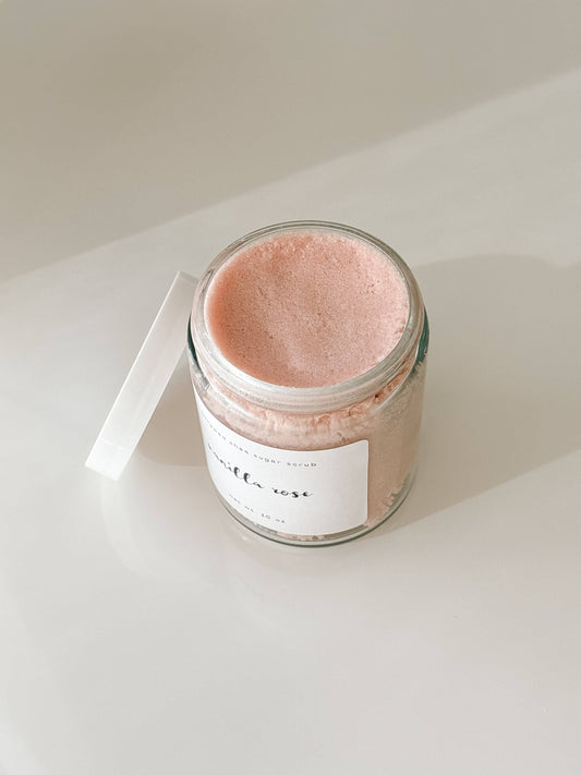 Jar of pink bath sugar scrub with a white label on a light surface