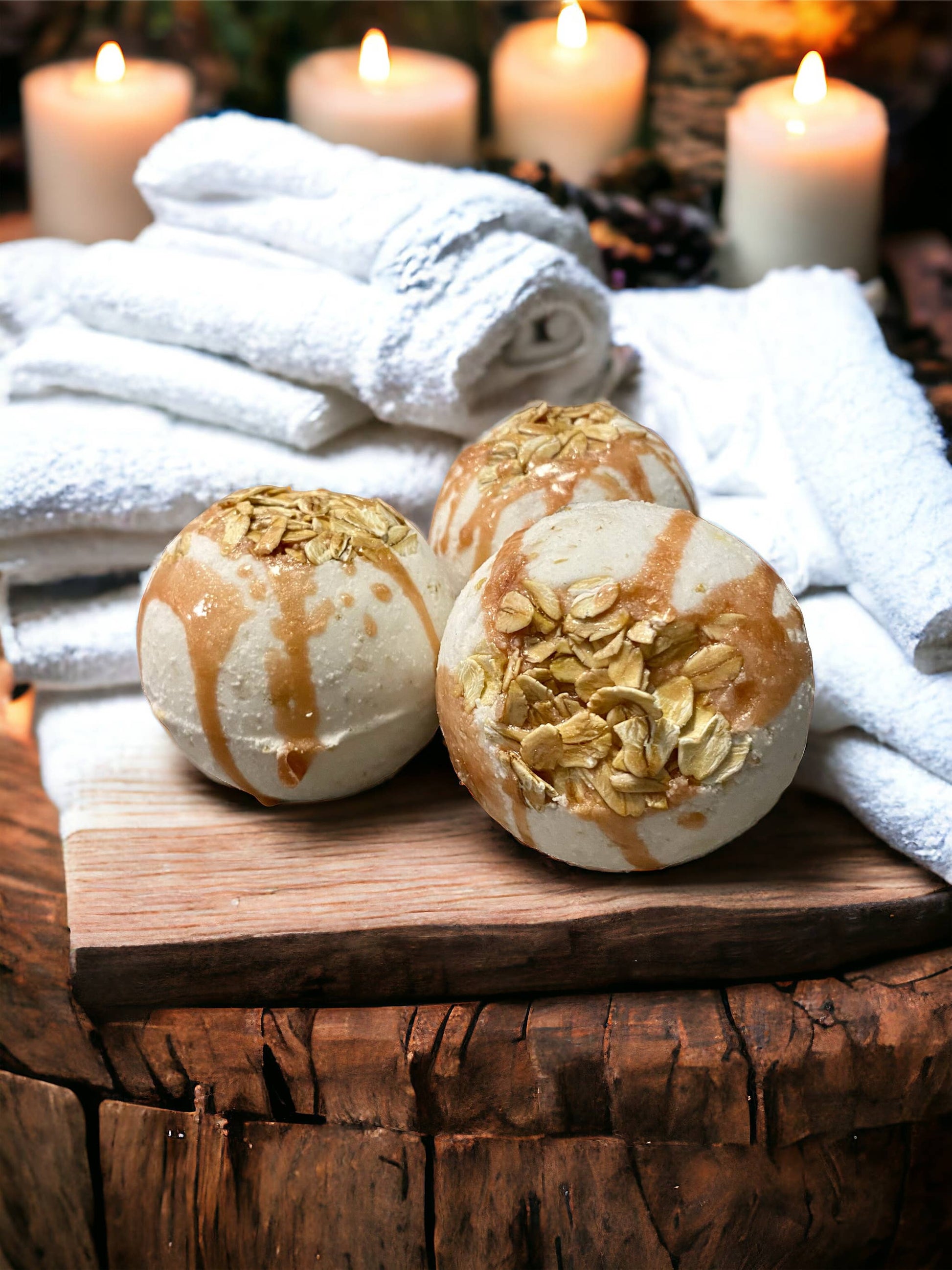 Bath bombs with oats on a wooden surface with white towels and candles in the background