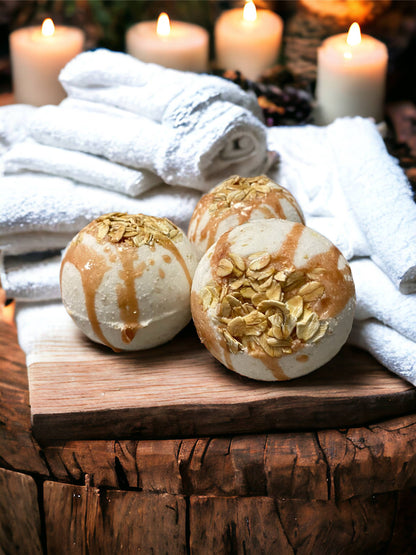 Bath bombs with oats on a wooden surface with white towels and candles in the background