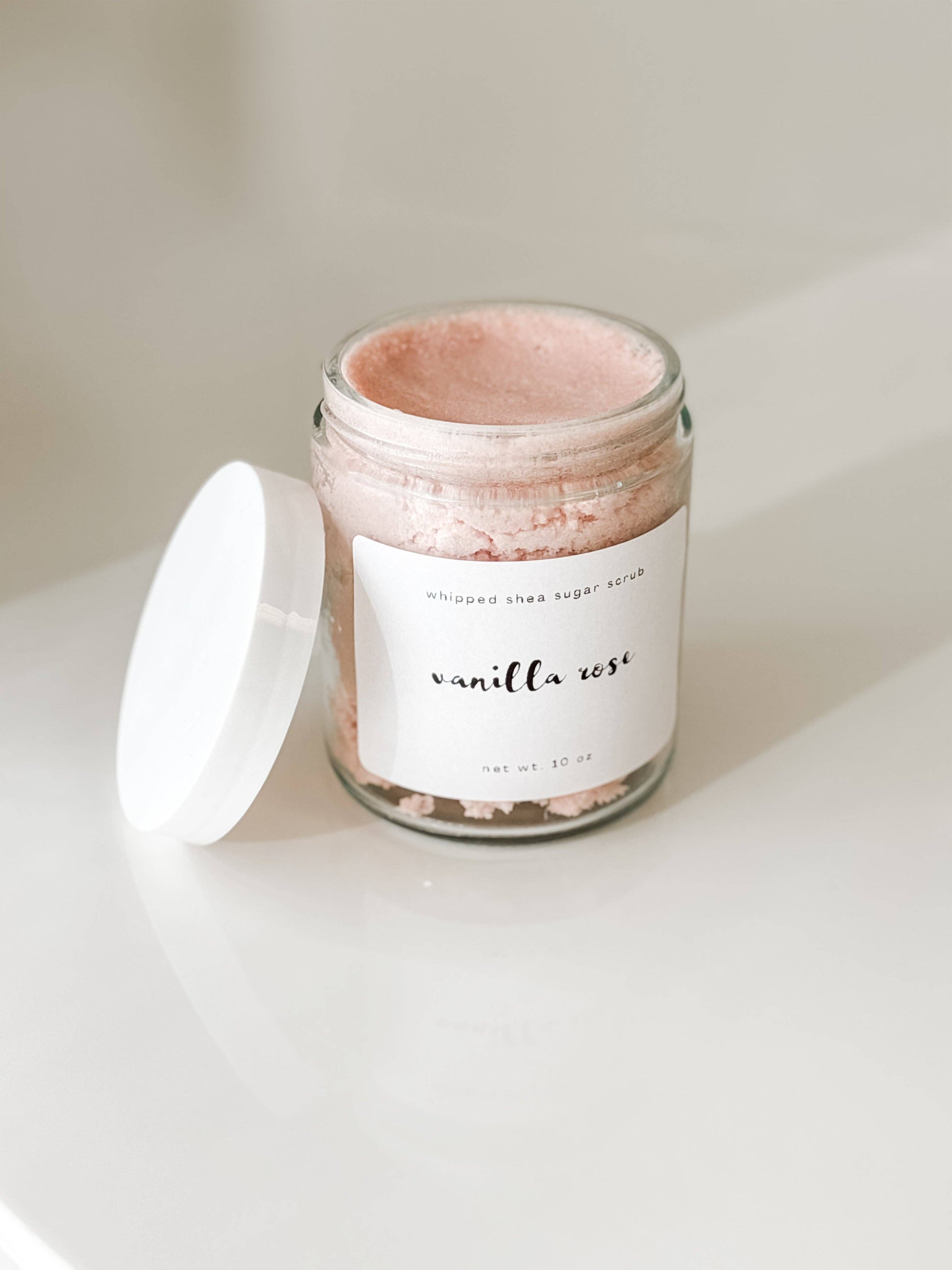 Jar of pink sugar scrub with a white label that read "Vanilla Rose" on a light background