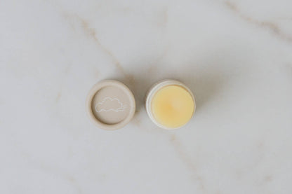 Two small round containers with beige lids on a marble surface