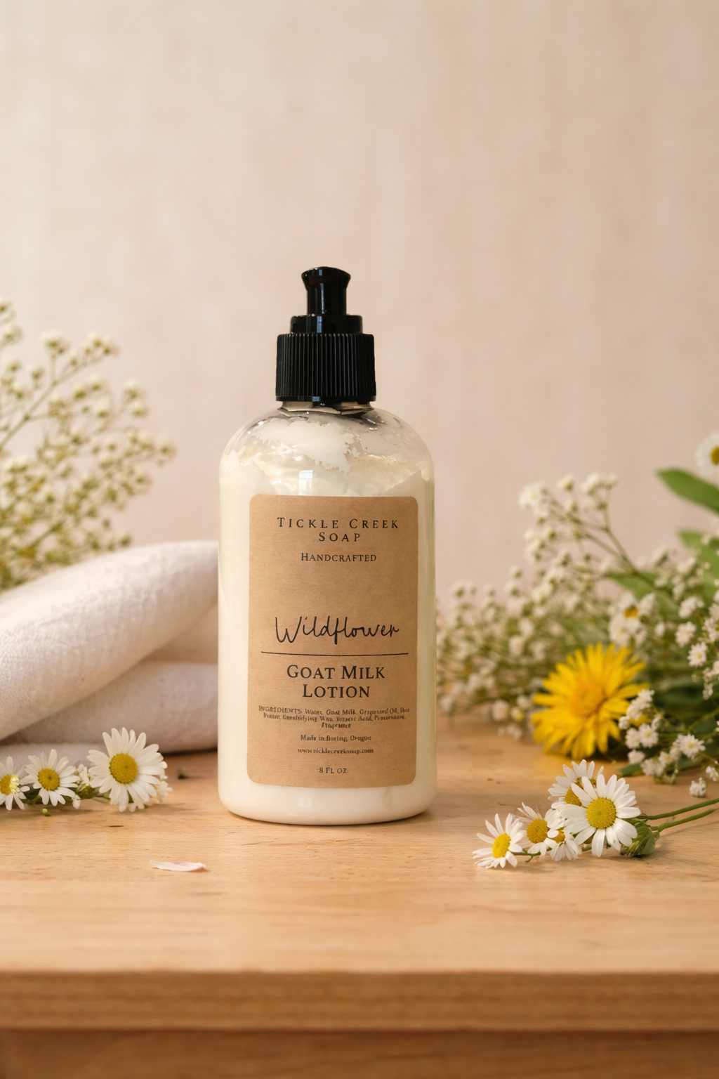 Bottle of Goat Milk Lotion with "Wildflower" on label and flowers on a wooden surface